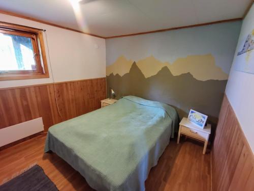 a bedroom with a bed and a mountain mural on the wall at Loghouse apartment in arctic wonderland! in Kvaløya
