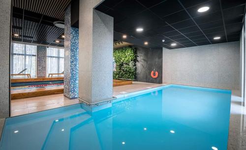 a swimming pool with blue water in a building at Seaside apartment Albatross, spa and pool in Ķesterciems
