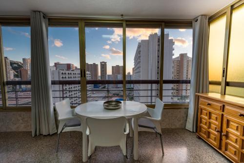 ベニドルムにあるOne bedroom Flat with shared pool in Acuarium IIの窓付きの客室で、白いテーブルと椅子が備わります。