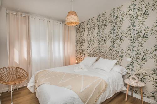 um quarto com uma cama branca e papel de parede floral em El Refugio de Sabina em Arenas de San Pedro