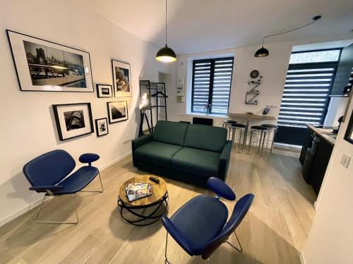un salon avec un canapé vert et des chaises dans l'établissement Hypercentre de Vienne appartement contemporain proche LYON, à Vienne