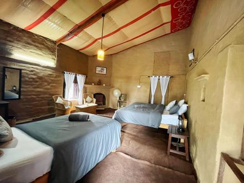 1 dormitorio con 2 camas y chimenea en Kurmanchal Village by THE GHAUR, en Almora