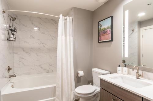 a white bathroom with a tub and a toilet and a sink at Kasa Downtown Austin in Austin
