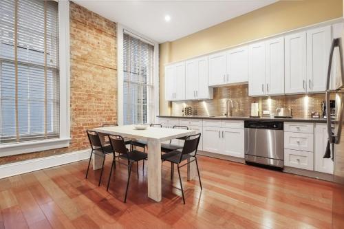a kitchen with white cabinets and a table and chairs at Roami at Factors Row in New Orleans