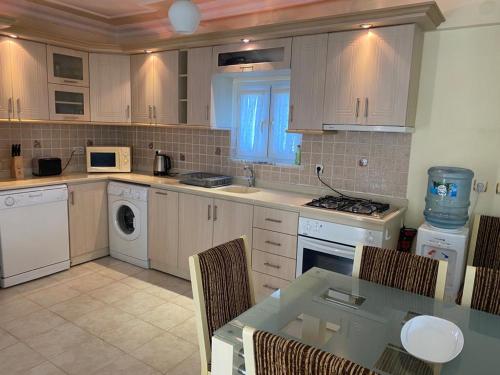 a kitchen with white appliances and a table with chairs at Three Bed villa, Private Pool in Didim