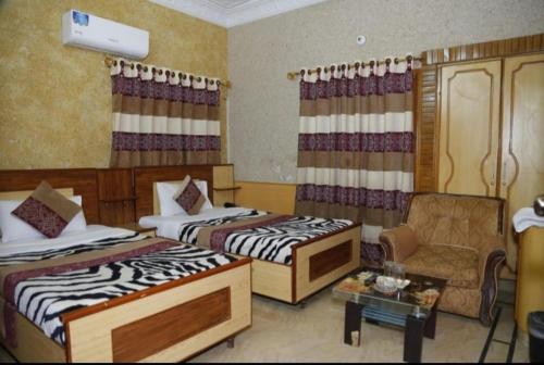 una habitación de hotel con 2 camas y una silla en Jinnah Airport Hotel en Karachi