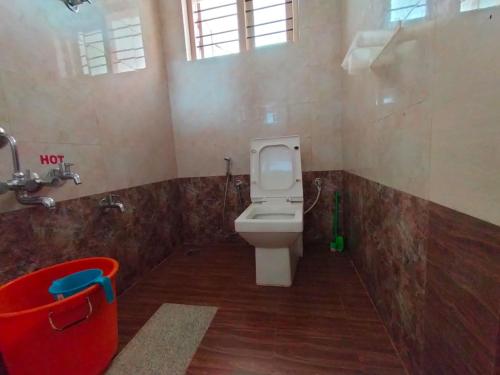a bathroom with a toilet and a red bucket at Snowdrop inn coorg in Madikeri