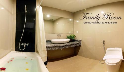 a bathroom with a sink and a toilet and a tub at Grand Asia Hotel in Makassar