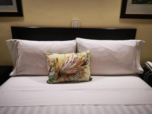a bed with white pillows and a pillow on it at Hotel Sin Escala in Palmira