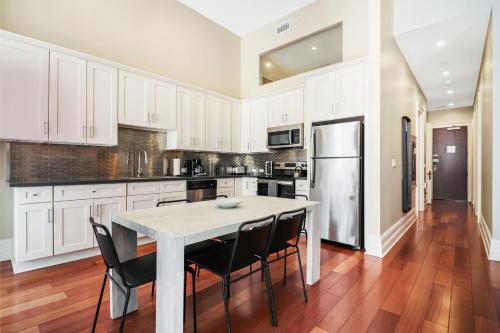a kitchen with white cabinets and a table and chairs at Roami at Factors Row in New Orleans