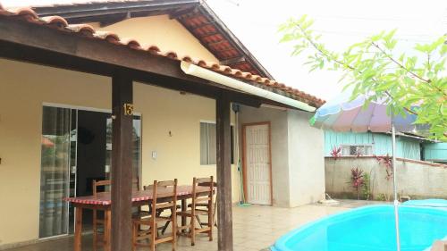 une maison avec une table et des chaises à côté d'une piscine dans l'établissement Casa B com Piscina Enseada Ubatuba Max06 Hosp, à São Francisco do Sul