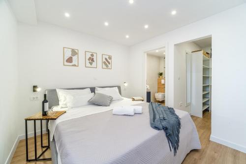 a white bedroom with a large bed and a table at Kuća za odmor INK in Nerežišće