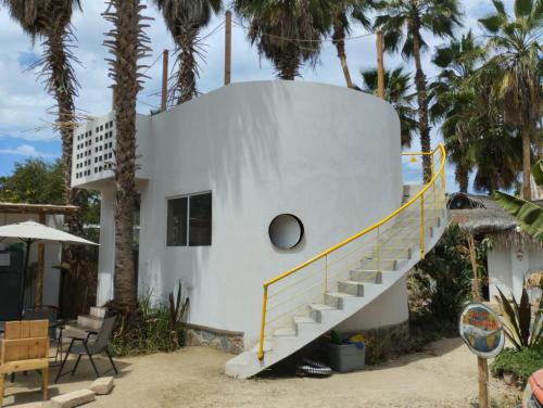a house with a spiral staircase in front of palm trees at La Sardina in Todos Santos