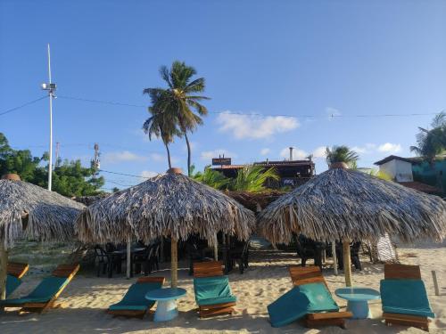 Pousada Paradise Flecheiras في ترايري: مجموعة من الكراسي ومظلات القش على الشاطئ