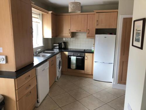 a kitchen with wooden cabinets and a white refrigerator at Self catering Oranmore in Oranmore