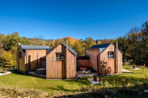 a group of three wooden houses on a grass field at 4 DOMY in Dolní Morava