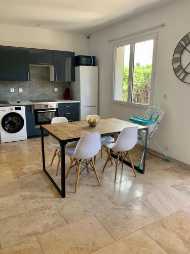- une cuisine avec une table en bois et des chaises blanches dans l'établissement Appartement à 200m des plages., à Fréjus