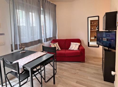 sala de estar con mesa y sofá rojo en DMC Residence - Alloggi Turistici en Anzio