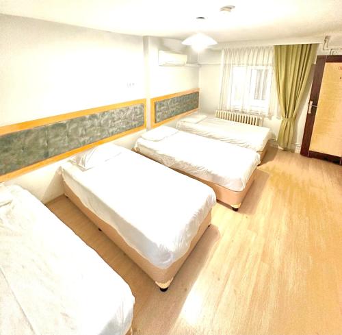 three beds in a room with wooden floors at Kestanbol Hotel in Canakkale