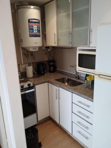 a kitchen with white cabinets and a sink and a microwave at Departamento Zona Puerto De Olivos in Olivos