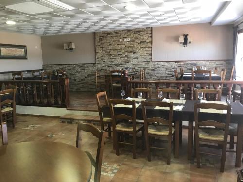 una sala da pranzo con tavoli, sedie e un muro di mattoni di LA CASA DEL SECRETARIO a Sotos