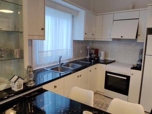 una cucina con armadi bianchi, lavandino e finestra di Sea view a Karpathos