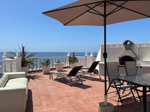 taras ze stołem, krzesłami i parasolem w obiekcie 1st Line Sea View & Rooftop - Arena w mieście Puerto de Santiago