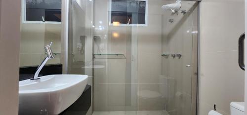 a bathroom with a glass shower and a sink at Aurora Hotel in Ribeirão Preto
