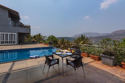 a patio with a table and chairs next to a pool at Tranquil Mulshi Villa with 4 Bedrooms in Mulshi
