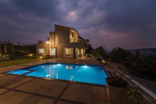 a swimming pool in front of a house at night at Tranquil Mulshi Villa with 4 Bedrooms in Mulshi