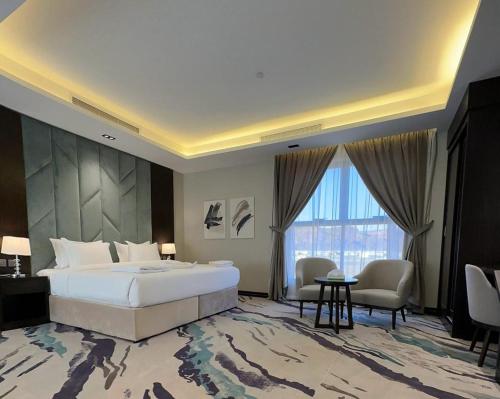 a bedroom with a large bed and a large window at فندق الوتين ALwateen Hotel in Al-ʿUla