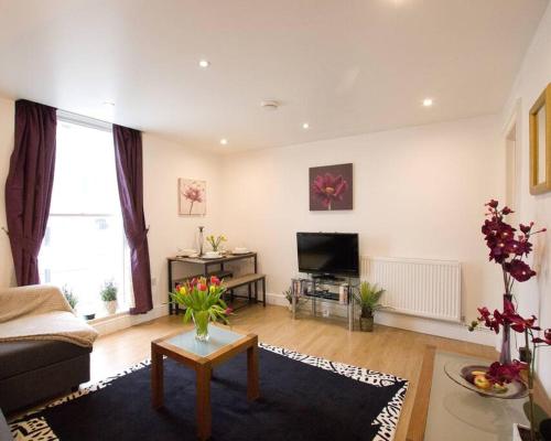 a living room with a couch and a tv at Cosy 1 Bedroom Apartment - Newbury High Street in Newbury