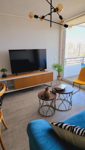 ein Wohnzimmer mit einem TV, einem Sofa und Tischen in der Unterkunft Departamento en Antofagasta 2D+1B FULL in Antofagasta