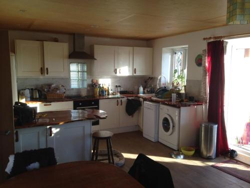 a kitchen with white cabinets and a washer and dryer at Apple tree House in Saltdean