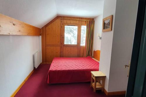 sypialnia z czerwonym łóżkiem i oknem w obiekcie Valloire-Appt 3*-8 pers-Piscine-Rés. le Galibier w mieście Valloire