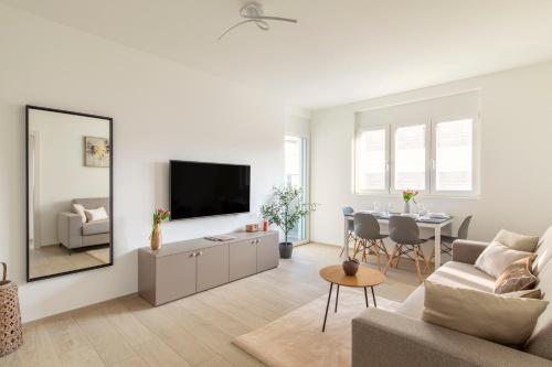 a living room with a television and a table with chairs at Lugano Superior Suites - Free Parking in Lugano