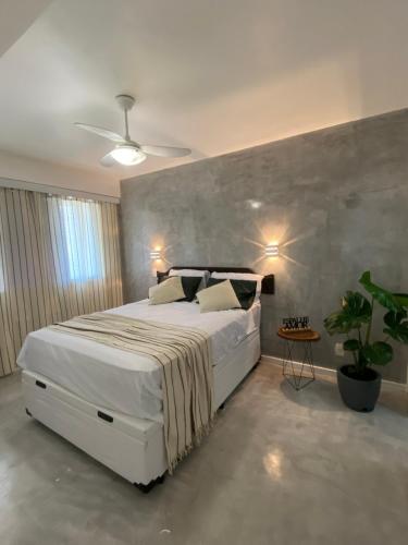 Un dormitorio con una gran cama blanca y una planta en Lifestyle Carioca Pontal Recreio, en Río de Janeiro