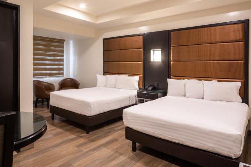 a hotel room with two beds and a chair at Hotel Astor Tijuana in Tijuana