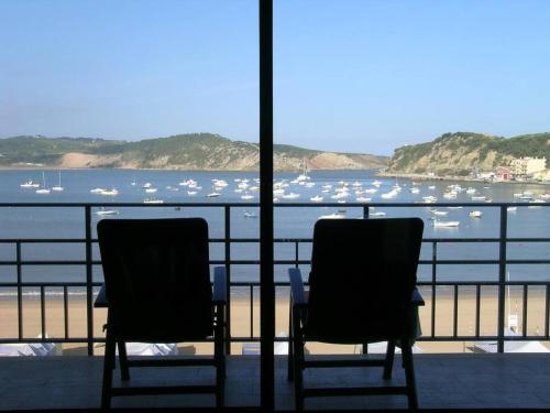 two chairs sitting on a balcony looking at the water at Apartamento em frente à Praia in São Martinho do Porto