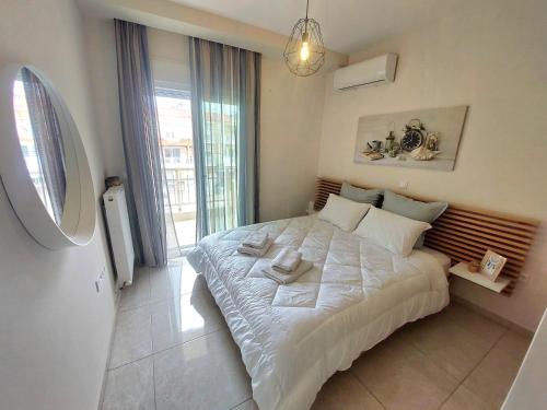 a bedroom with a large white bed with a window at Myrsini’s sea view apartment in Nea Peramos