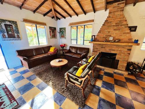 a living room with couches and a brick fireplace at Disfruta nuestro bello paraíso ! in La Ceja