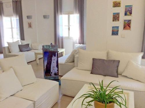 a living room with white couches and a plant at Aegialis Hotel & Spa in Aegiali