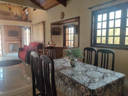 a dining room with a table and chairs and a room with a couch at Chácara Recanto da Mata in Cunha