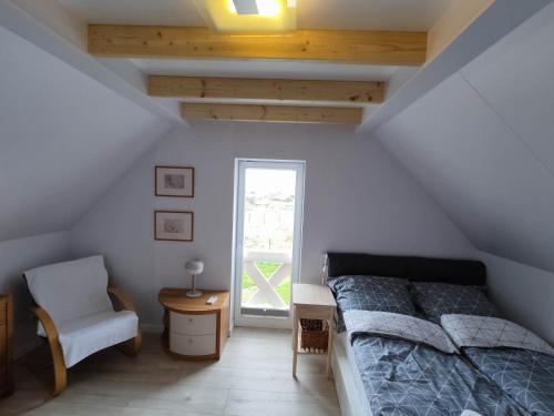 a bedroom with a bed and a chair and a window at Baltic Rafa in Niechorze