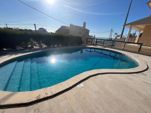 a large swimming pool with blue water in a yard at Azenhas Apartment in Sintra