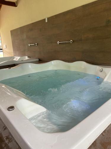 a bath tub filled with blue water in a bathroom at Flat E311 - Aldeia das águas in Barra do Piraí