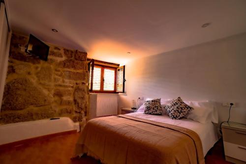 a bedroom with a bed and a stone wall at A Casiña dos Canastros in Barcia