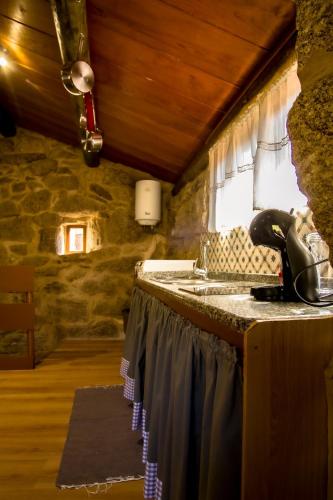 a kitchen with a counter with a sink and a window at A Casiña dos Canastros in Barcia