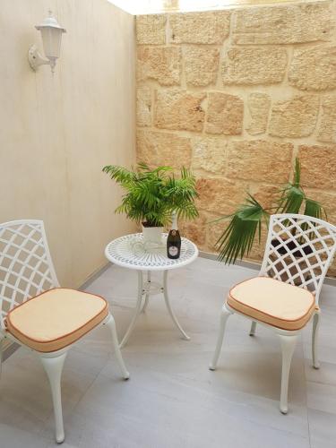 a patio with two chairs and a table with a plant at Tal-Kampjin in Mellieħa