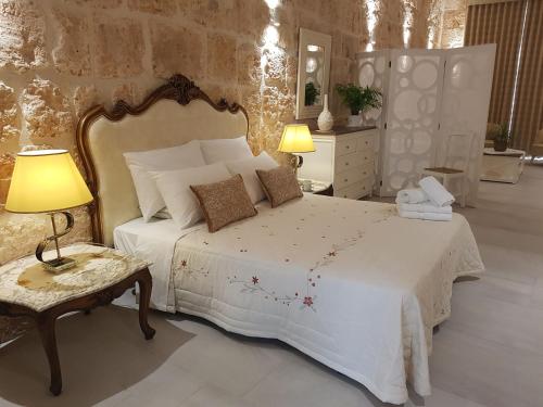a bedroom with a white bed and a table and lamps at Tal-Kampjin in Mellieħa